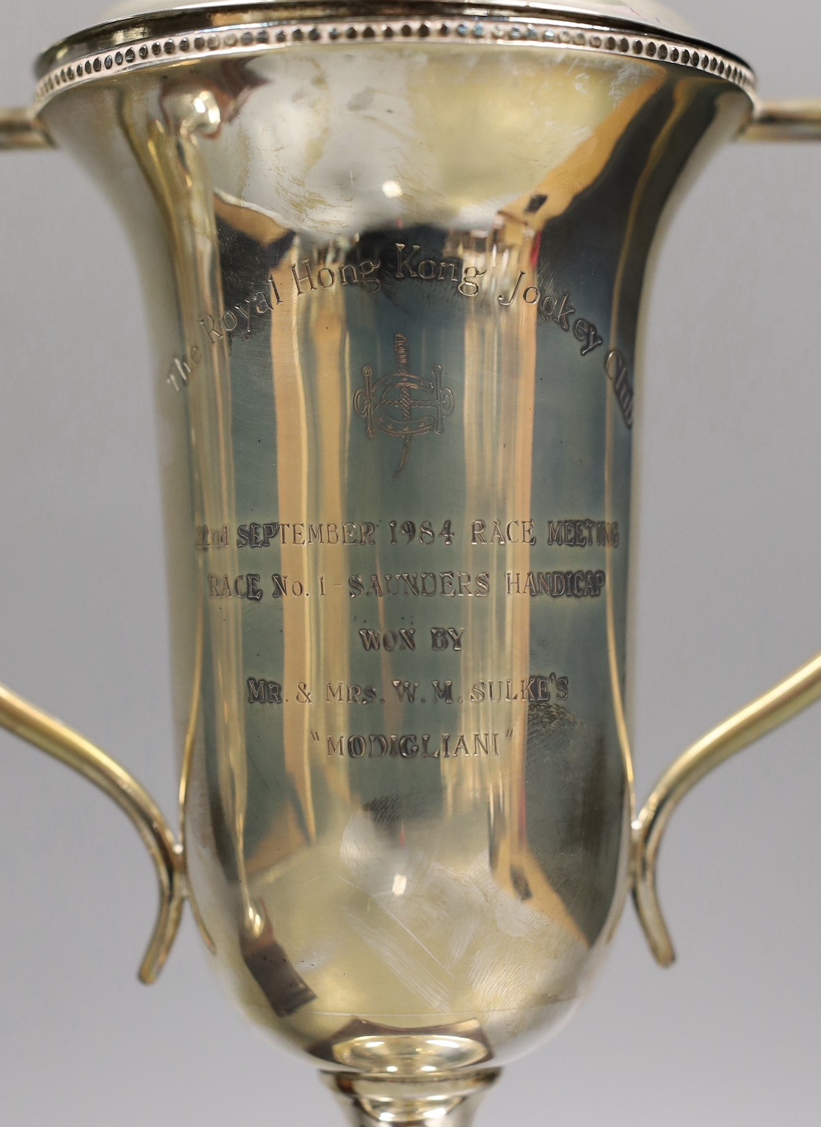 A pair of Royal Hong Kong Jockey Club sterling presentation two handled trophy cups and covers, fixed to wooden plinth bases, height of cups 26cm.
